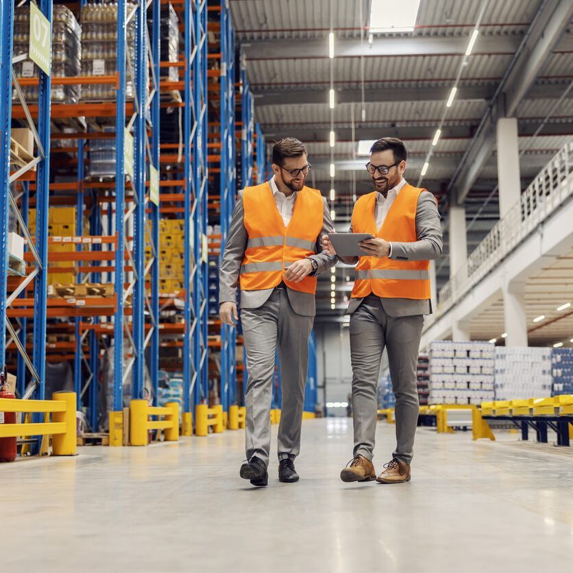 Businesspeople dispatching warehouse and smiling at the tablet.